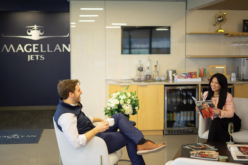 two people sitting in chairs in Magellan Jets private terminal