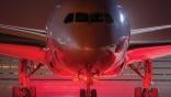 Front view of aircraft on runway, lit up in red