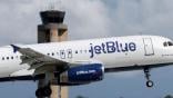 JetBlue aircraft flying near an air traffic control tower