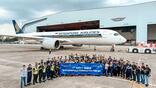 employees in front of an aircraft and holding a sign regarding the first Singapore Airlines A350 C-check