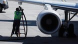 worker carrying refueling tube by aircraft