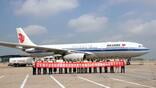 air china team members holding ceremonial banner in front of aircraft