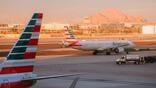 american airlines aircraft taxis at airport, framed by another aircraft's striped tail