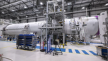 aerospace manufacturing hangar with a white cylindrical spacecraft 