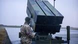 a military operator stands beside a nasams system