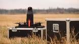 quadcopter drone next to a grey equipment case in a field