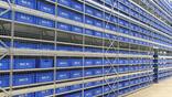 warehouse shelving holding rows of blue labeled storage bins