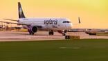 volaris aircraft taxis past airport grass at sunset