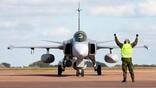 ground crew member in vest guides jas 39 gripen fighter jet