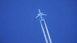 aircraft ascending leaving contrails in a dark blue sky