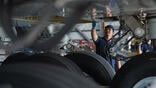 technician inspecting landing gear and underside of an aircraft wing