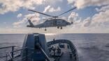 military helicopter above naval ship at sea