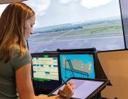 Student working on tablet by two monitors in air traffic control training