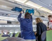 Three people, one placing bags into overhead bin