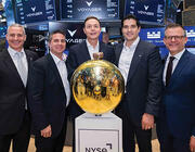 Five men standing around the bell at the New York Stock Exchange