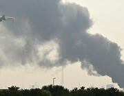 Emirates jet flying low with smoke plume in background