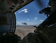 A crew member aboard one HH-60W watches another fly past during an exercise in Arizona in 2023.