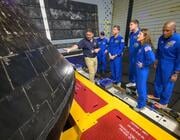 The crew of Artemis II inspect the outside of the Orion spacecraft in the well deck of the recovery vessel USS John P. Murtha, the day after their April 10 splashdown in the Pacific.