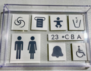 From left to right, top to bottom: flush, paper towel, changing table, trash can, lavatory, seat number, flight attendant call, wheelchair accessible.