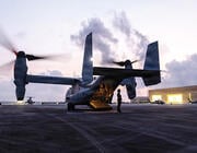Person standing by V-22 on runway