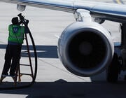 worker carrying refueling tube by aircraft