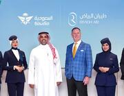 six people standing in front of screen showing Saudia and Riyadh Air logos and aircraft tails