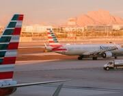 american airlines aircraft taxis at airport, framed by another aircraft's striped tail