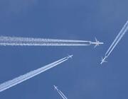 four aircraft in flight leaving white contrails across a clear blue sky