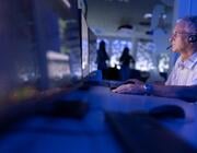 man working at computer in dark, blue-lit control room