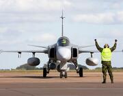 ground crew member in vest guides jas 39 gripen fighter jet