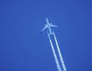 aircraft ascending leaving contrails in a dark blue sky