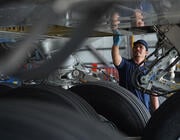 technician inspecting landing gear and underside of an aircraft wing