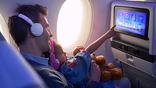 parent and child sitting on aircraft with inflight entertainment screen lit